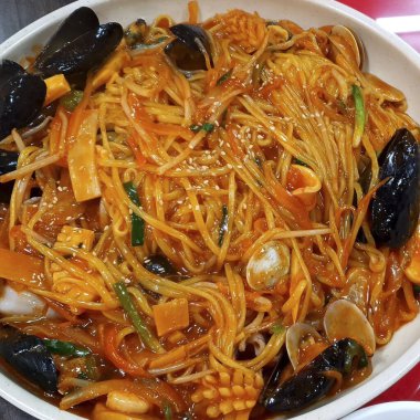 Karıştır - tavuklu ve sebzeli kızarmış erişte beyaz tabakta.