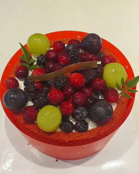 Bir kase taze meyve salatası, bir kaşık ve bir fincan süt.