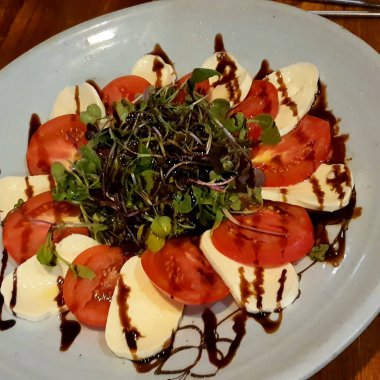 Domatesli salata, peynir, roka ve fesleğen beyaz ahşap bir masada, sağlıklı yiyecek konsepti.