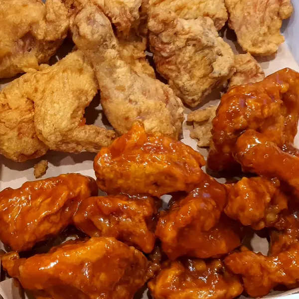 Tavuk kanatlarını ve kızarmış patatesleri beyaz tabakta yakın.