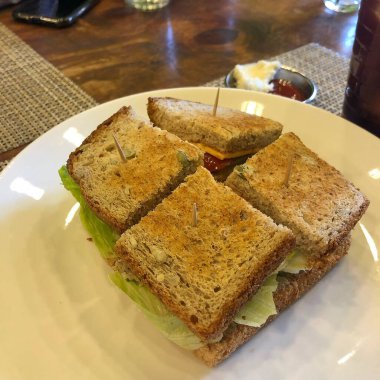 Beyaz tabaklı ve ahşap masalı bir sandviçin yakın plan fotoğrafı.