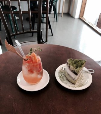 Tahta bir masanın üzerinde bir bardak kahveyle bir fincan kahve.