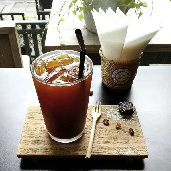 Kahve fincanı ve çay, ahşap masada buzlu.