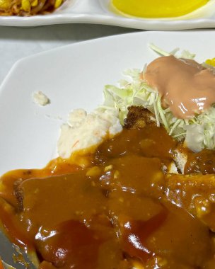 Beyaz tabakta tavuk ve patatesli lezzetli bir yemeğin yüksek açılı görüntüsü.