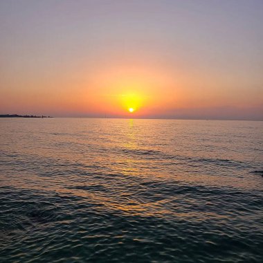 Dalgalar ve güneşle denizin üzerinde gün doğumu.