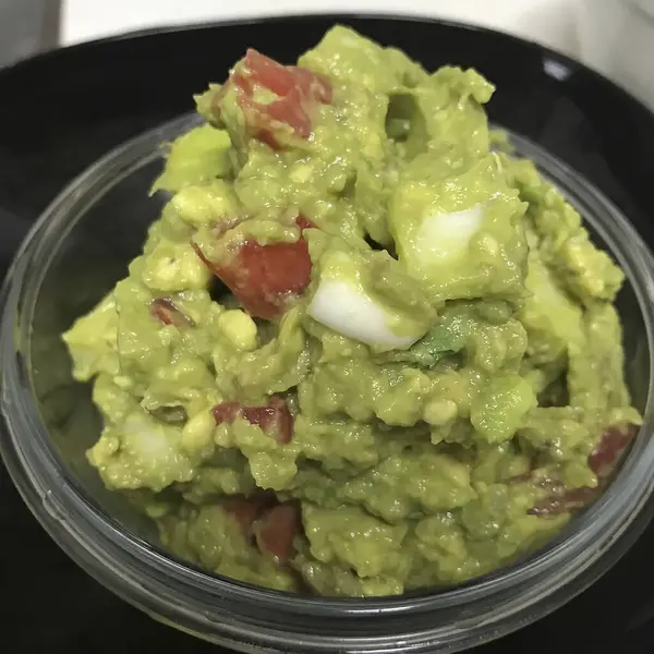 Domatesli guacamole ve beyaz tabakta limon.