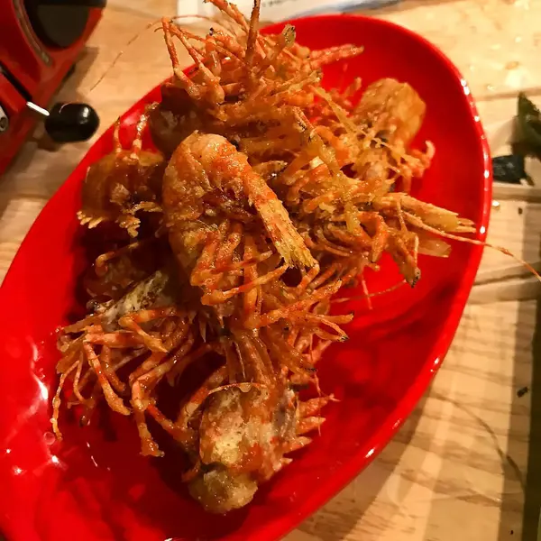 Tahta bir tabakta kızarmış karides ve sebzeler.