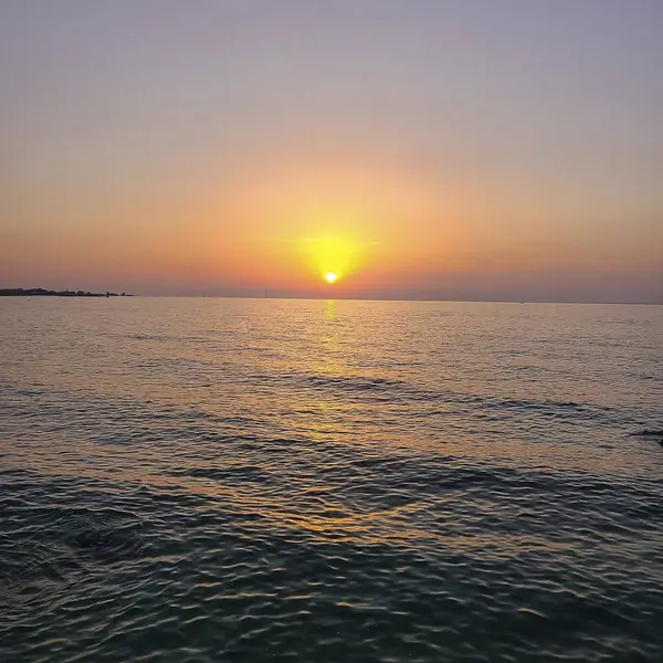 Dalgalar ve güneşle denizin üzerinde gün doğumu.