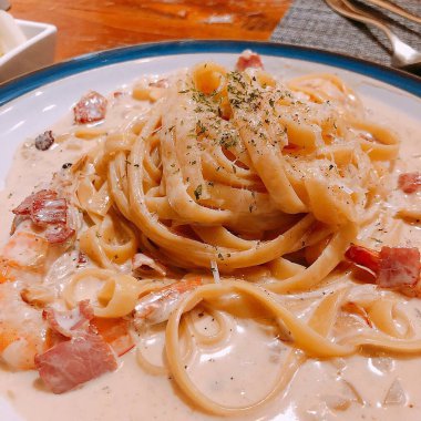 Beyaz tabakta deniz ürünleriyle kaplanmış spagetti.