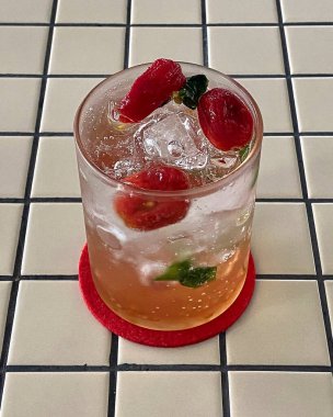 Gri arka planda bir bardak kırmızı limonata.