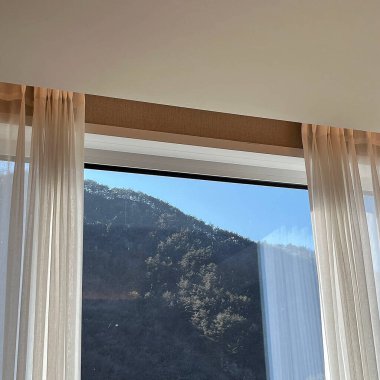 Sabah dağın tepesinde perdesi ve perdesi olan bir pencere.