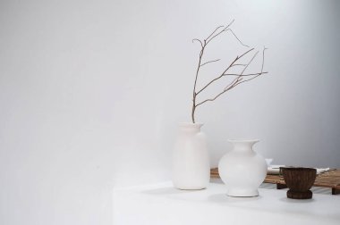 Masanın üzerinde beyaz vazo ve vazo var.