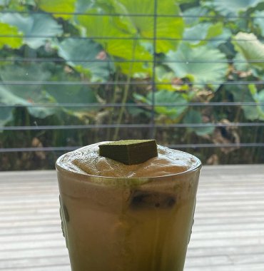 Ahşap masada yeşil yapraklı buzlu çay..