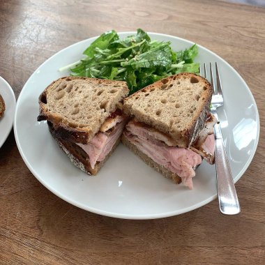 Masadaki beyaz tabakta sandviç.