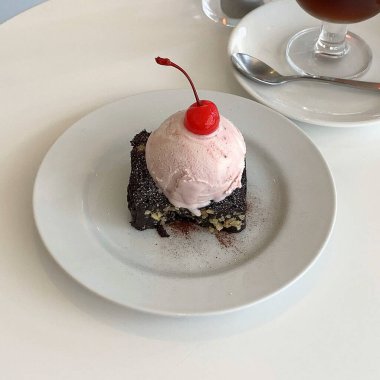 Dondurmalı çikolatalı pasta ve beyaz tabakta kiraz.