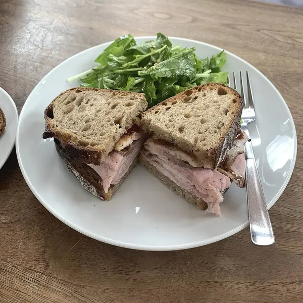 Masadaki beyaz tabakta sandviç.