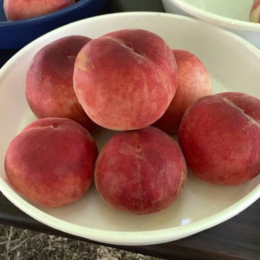 Tahta bir masada sepetin içinde olgun şeftaliler.