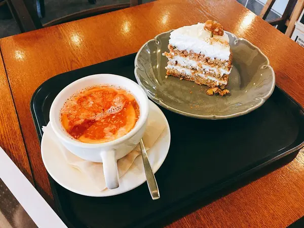 Bir fincan kahve, bir fincan kahve, bir kek ve ahşap bir masada bir parça kahve.