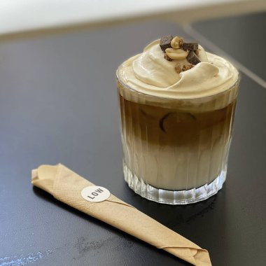 Tahta bir masada pipetli bir fincan latte.