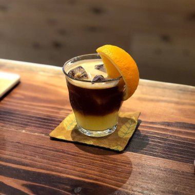 Bir bardak buzlu viski ve ahşap bir masada pipet.