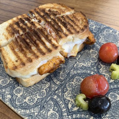 Tavuklu, domatesli, peynirli ve marullu bir tostun dikey fotoğrafı..