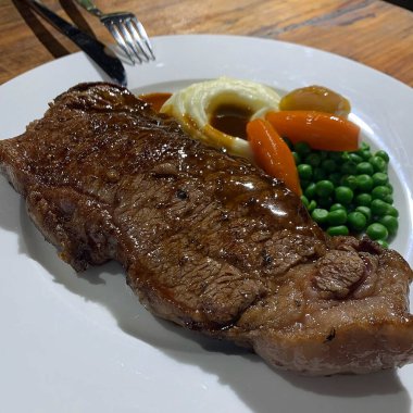 Patatesli ızgara biftek, yeşil fasulye ve sebzeler beyaz tabakta, yakın plan.