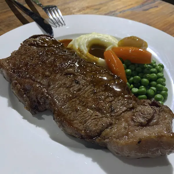 Patatesli ızgara biftek, yeşil fasulye ve sebzeler beyaz tabakta, yakın plan.