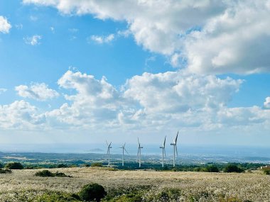 Mavi gökyüzü arkaplanlı yeşil alanda rüzgar türbinlerinin görüntüsü