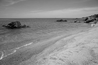 Kayalık bir sahilde küçük dalgalı siyah beyaz deniz manzarası