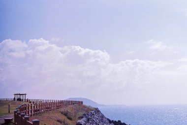 Mavi gökyüzünün arka planında denizi olan bir uçurum manzarası