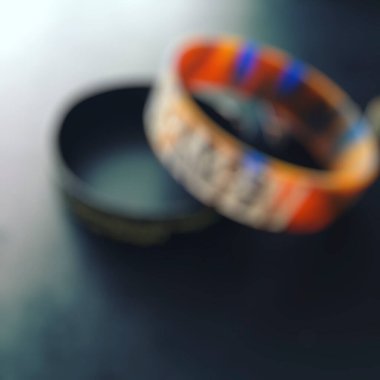 Ahşap yüzeyde, bulanık ışıkları olan renkli alyansların yakın çekimi.