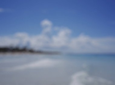 Beyaz kum ve mavi gökyüzü ile tropikal denizin bulanık arkaplanı.