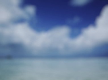 Mavi gökyüzü ve beyaz bulutlu bulanık sahil manzarası.