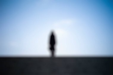 Yolda yürüyen genç bir kadının silueti.