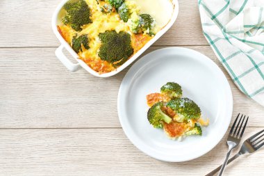 Beyaz ahşap bir masada, peynir ve krema soslu güveç brokoli..