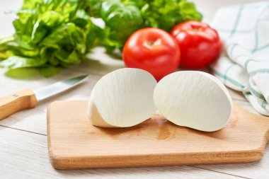 Beyaz İtalyan yumuşak peyniri Mozzarella di Bufala Campana topu taze yeşil fesleğen ve kırmızı domates ile servis edilir..