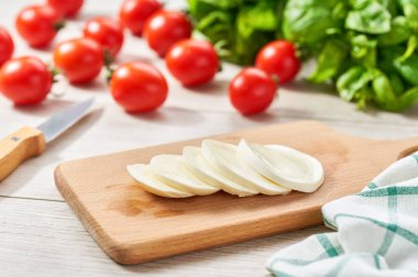 Mozzarella cheese balls with tomato and basil on a white kitchen table. homemade organic mozzarella cheese with tomato and basil.