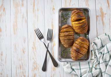 Klasik kızarmış Hasselback patatesi. Fırın tepsisinde, ahşap masada, manzaralı. Metin için alanı kopyala.