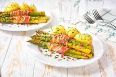 Beyaz masada yeşil kuşkonmaz ve haşlanmış patates, seçici bir odak noktası.