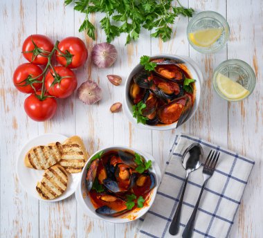 Geleneksel domates çorbası midyeli ve kızarmış baget ekmeği beyaz bir masada, üst tarafta..