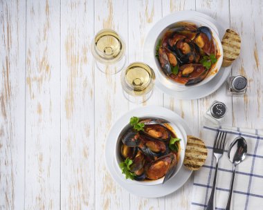 Çıtır ekmekle servis edilen domates soslu midyeler. Beyaz ahşap arka planda, istiridyeli lezzetli yemekler..