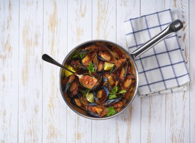 Tahta bir masada tavada domates sosunda pişirilmiş lezzetli midyeler, metin için spase kopyaları..