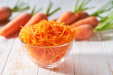 Beyaz ahşap bir masada taze rendelenmiş havuçlar, seçici bir odak..