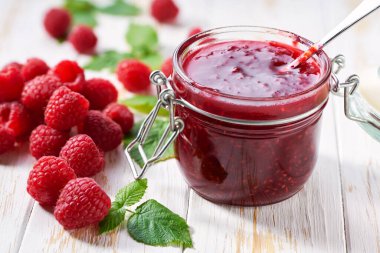 Cam kavanoz ahududu reçeli ve beyaz ahşap masada taze böğürtlen..