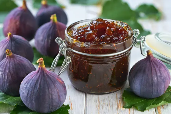 Figs jam in jar and ripe figs on a wooden table. Figs marmalade or jam in glass jar.