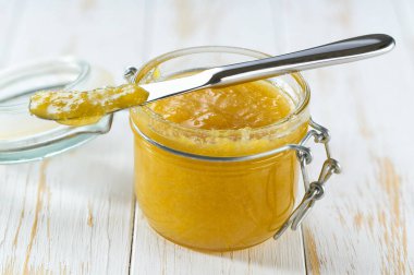 Beyaz ahşap bir masada limon reçeli kavanozu.