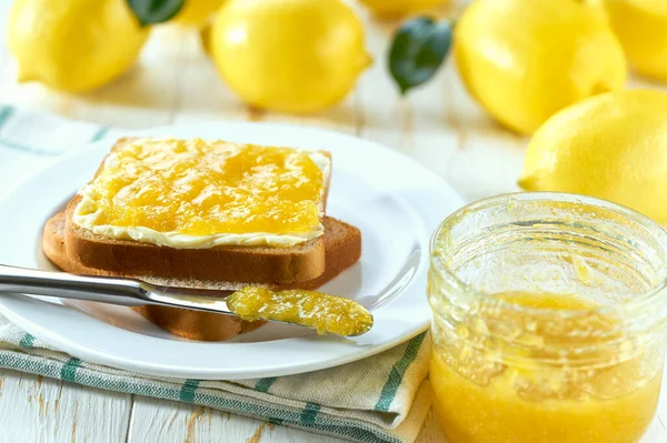 Plate with slices of bread and delicious lemon jam on wooden table. Toast with tasty lemon jam on a white wooden table.