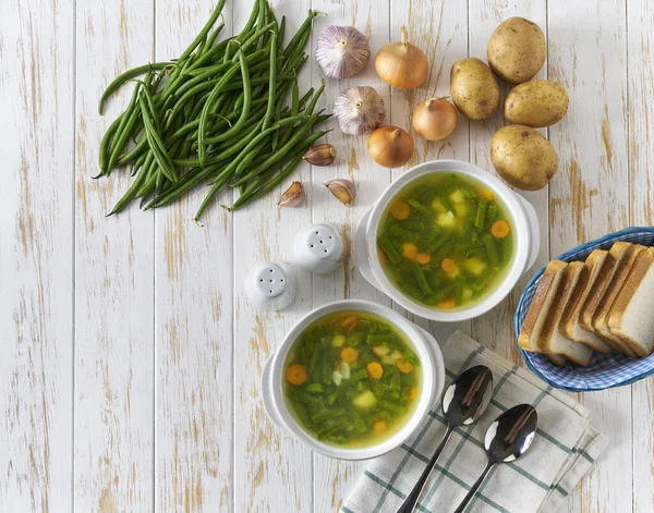 vegetarian dish, dietary delicious soup of green beans on a white wooden table, top view. healthy detox food or vegetarian food