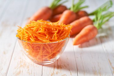 Beyaz ahşap bir masada taze rendelenmiş havuçlar, seçici bir odak..