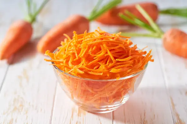 grated carrots on a white wooden table,  selective focus.